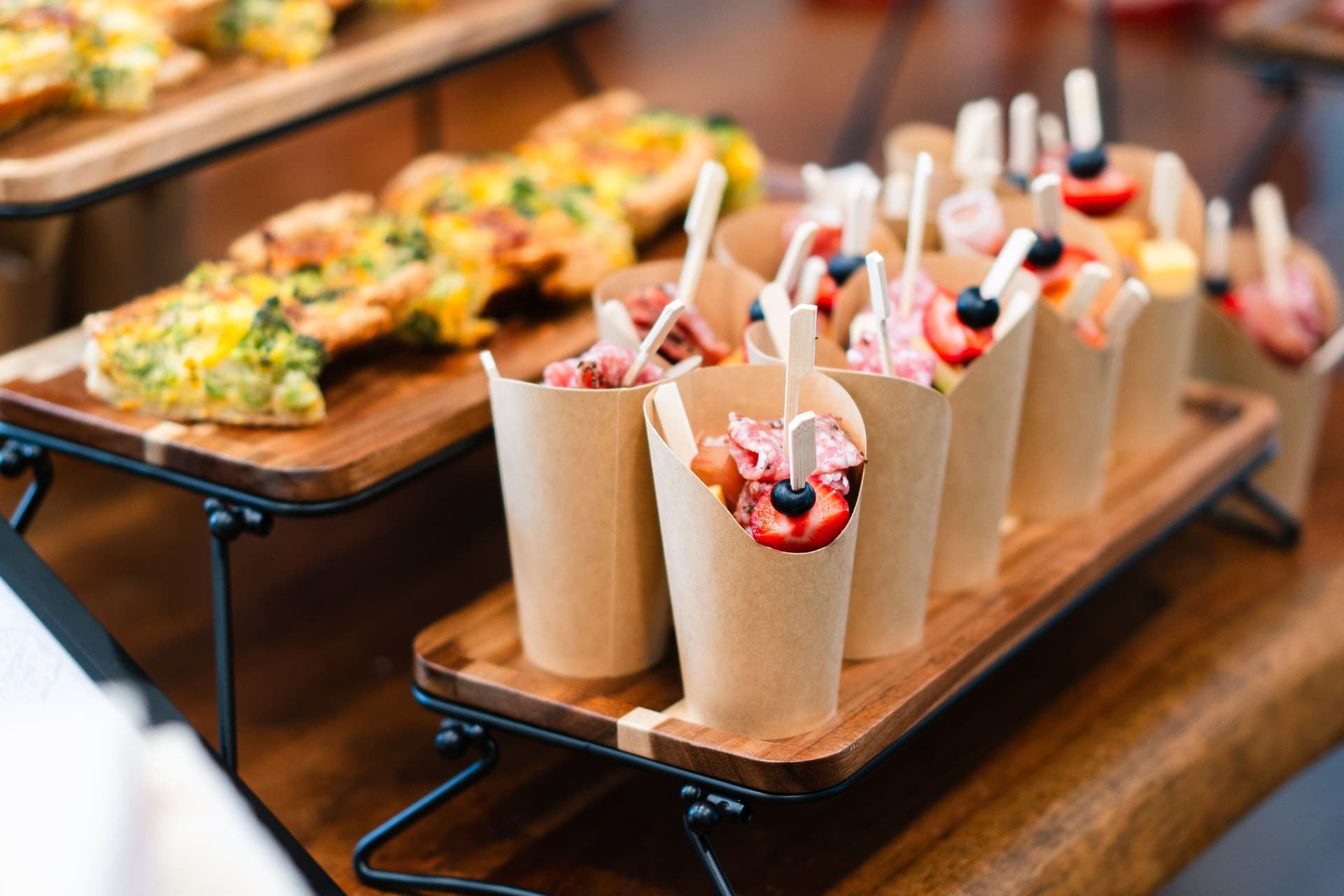 Individual fruit and yogurt cups beside quiche bites on a catering display