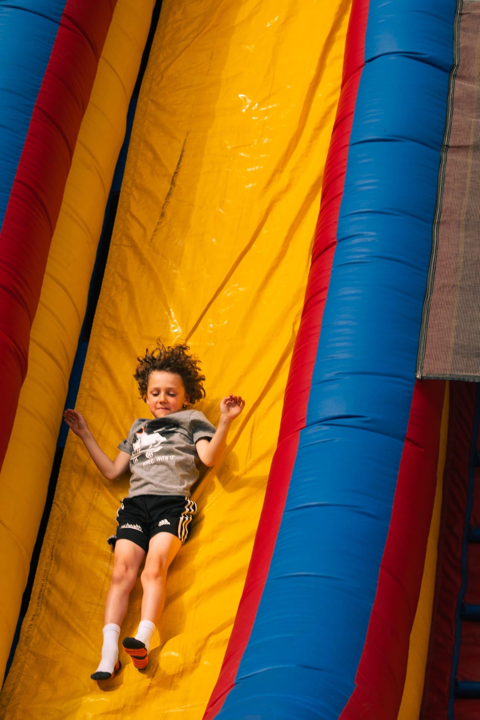 Child racing down an inflatable slide at Castle Pines Food Truck Frenzy