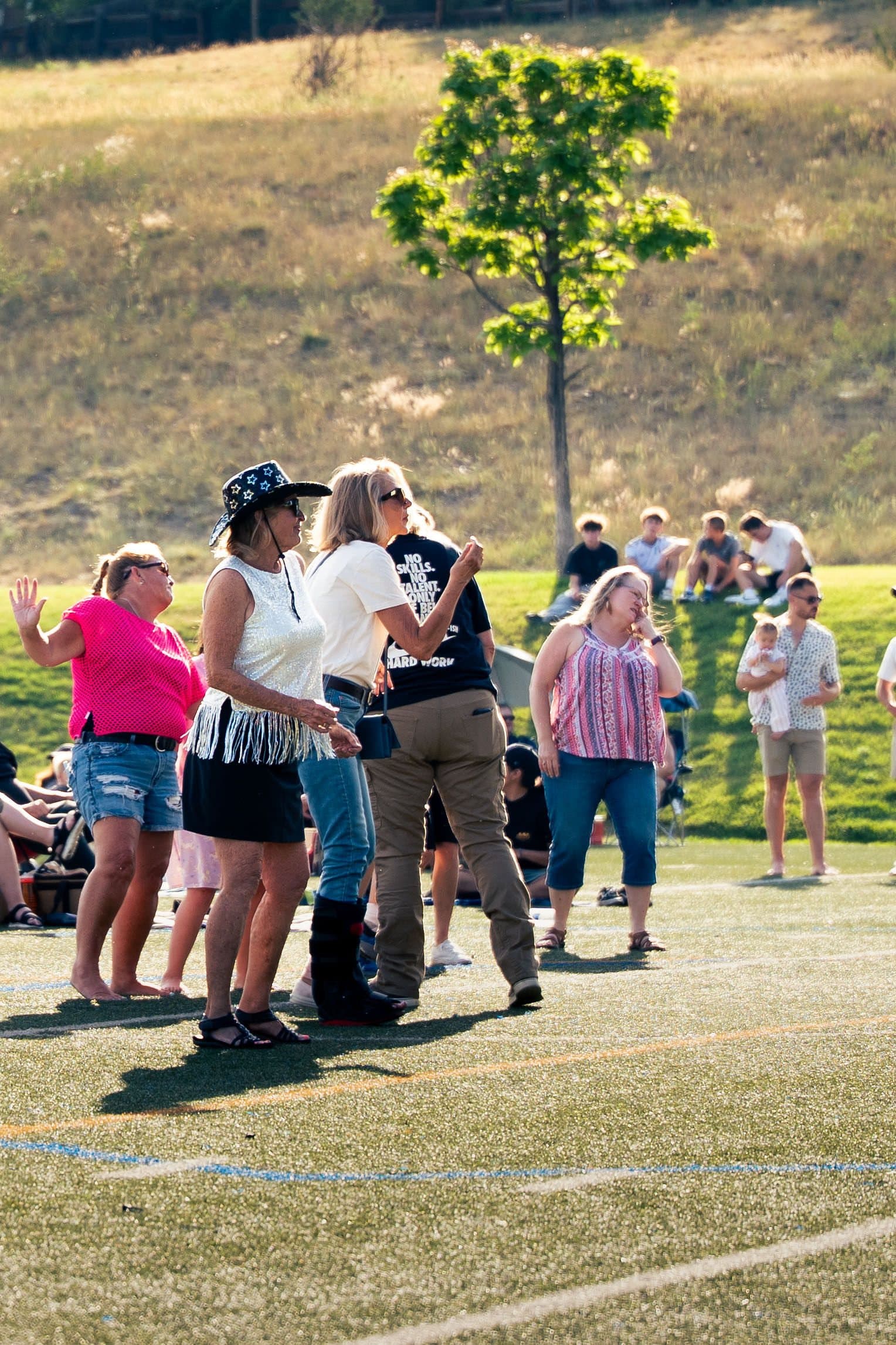 Friends dancing on the field at That Eighties Band concert in Castle Pines