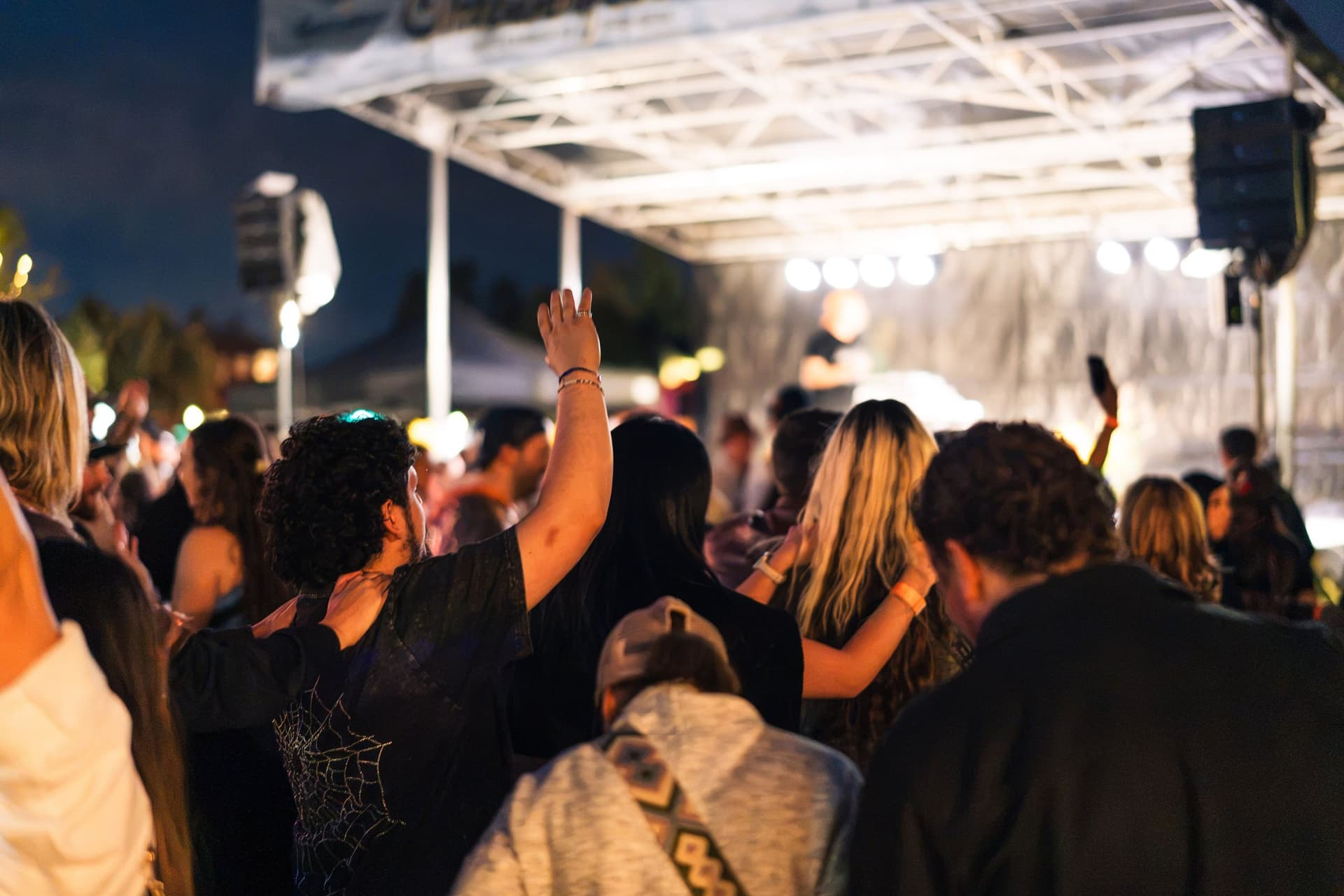 Night crowd with hands raised under the stage lights at Castle Rock Oktoberfest