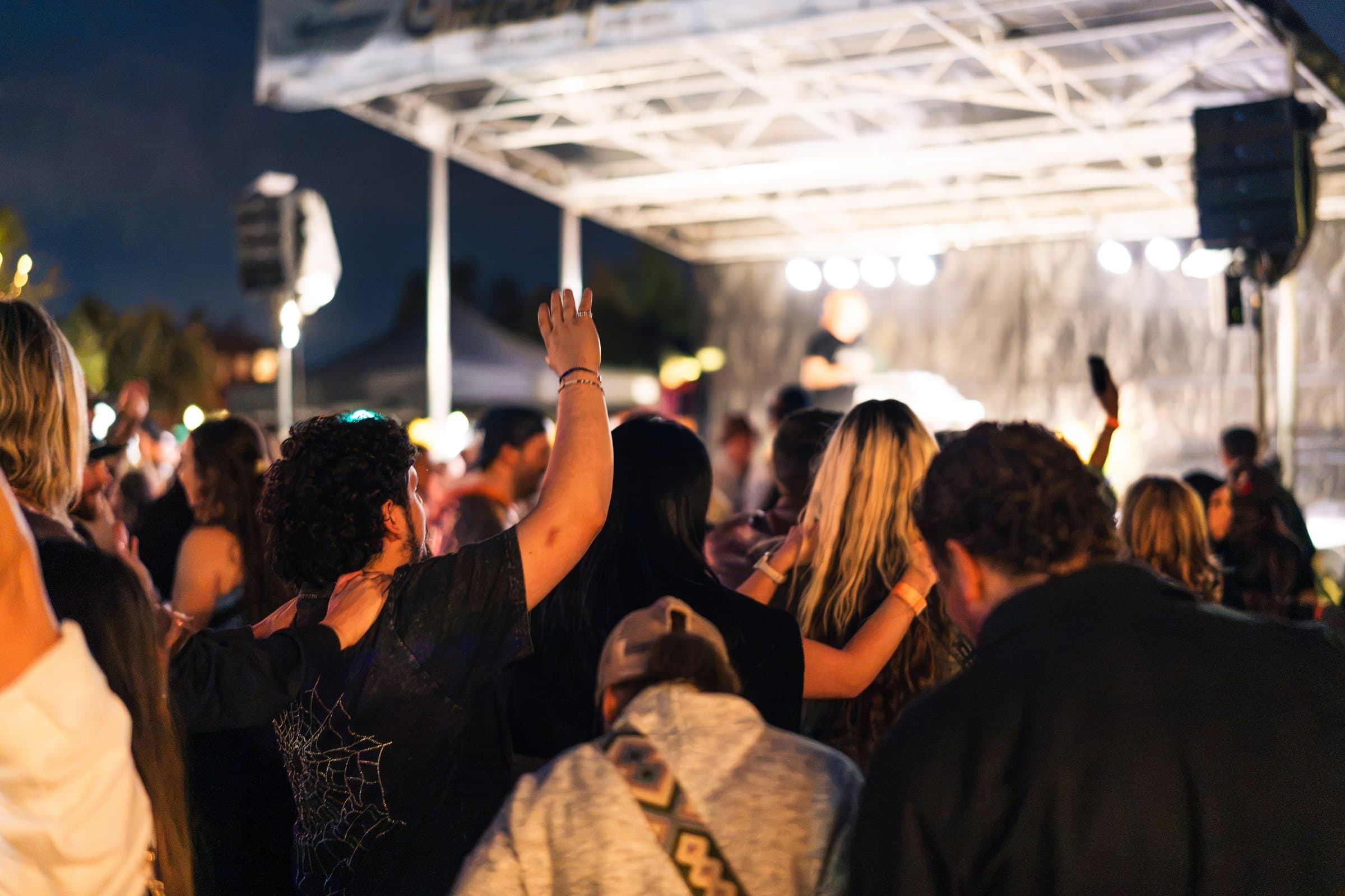 Night crowd with hands raised under the stage lights at Castle Rock Oktoberfest