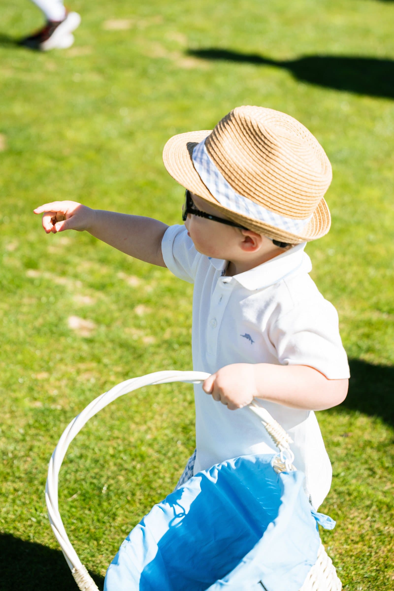 Toddler in a sun hat carrying a basket at the Easter egg hunt