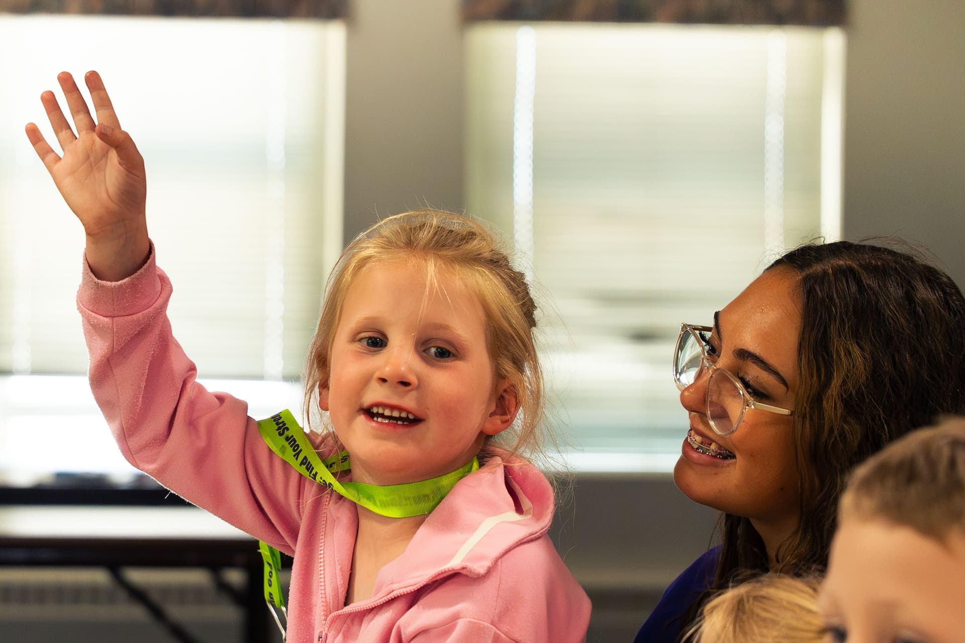 Girl raising her hand with a big smile during a VBS lesson