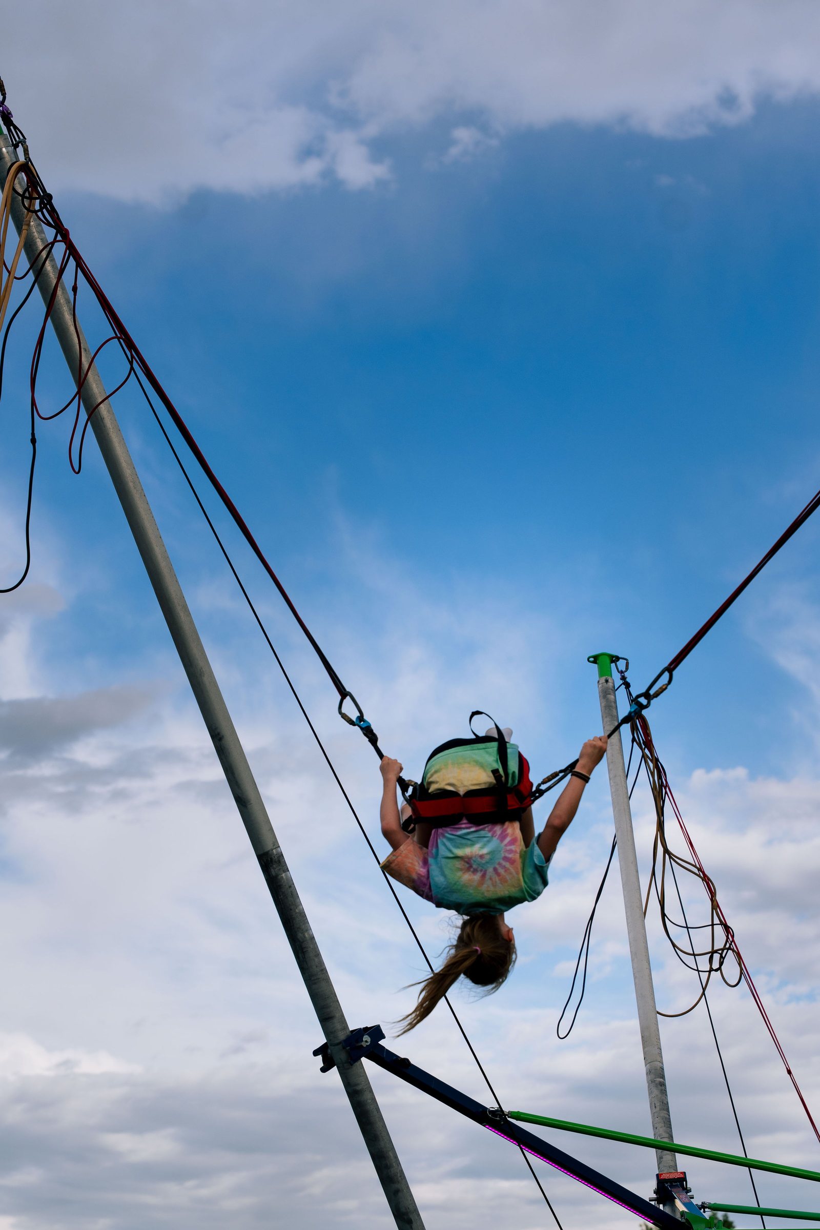 Bungee jumper high against a blue sky at a Castle Pines community festival