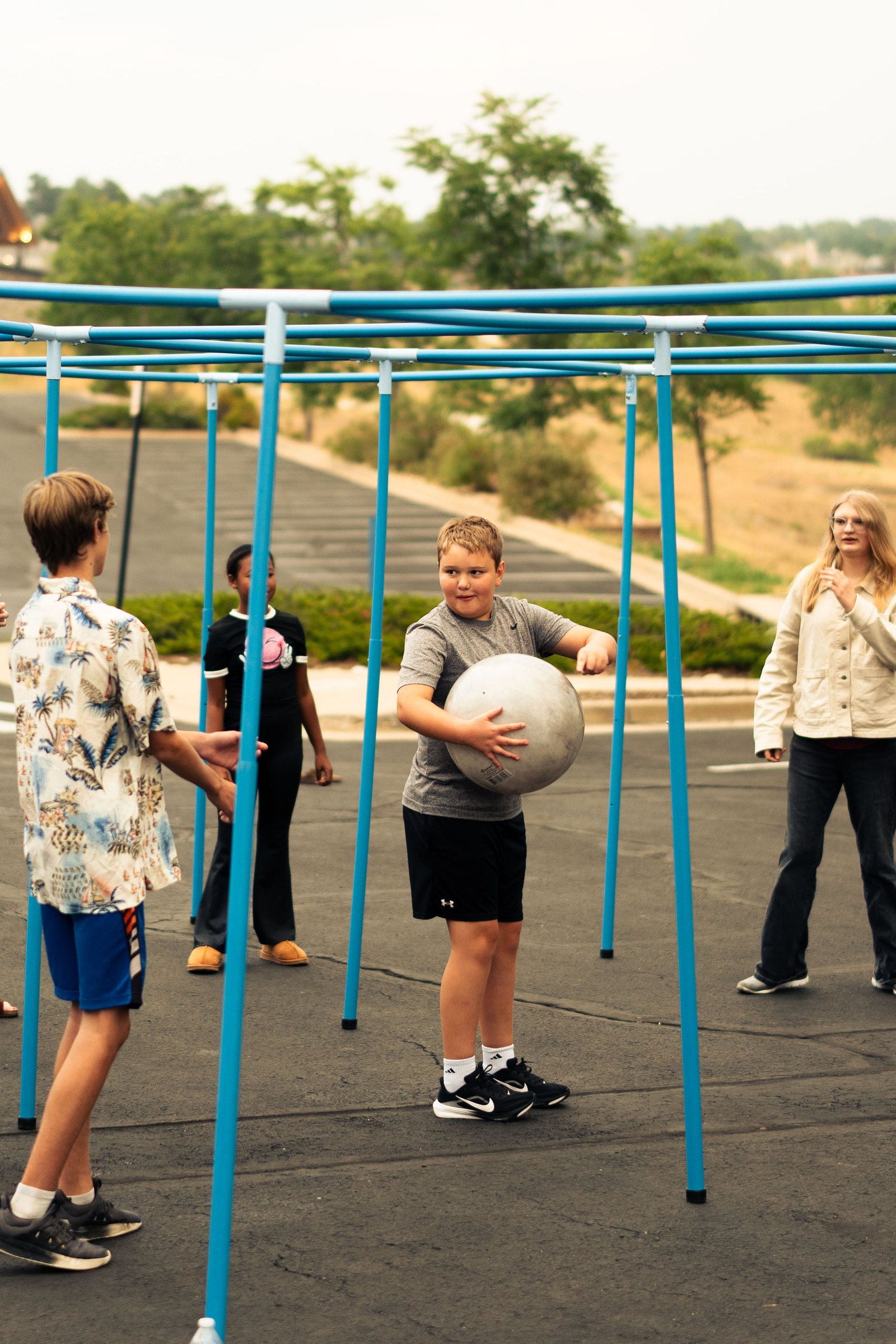 Youth group playing an outdoor game under a blue frame structure